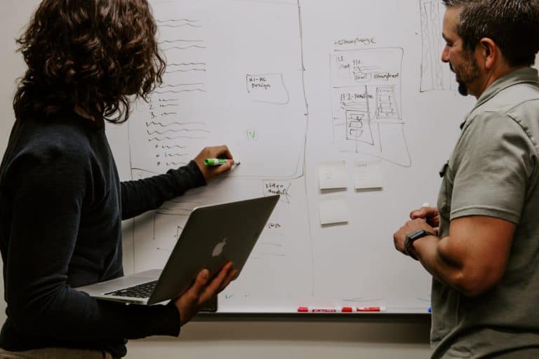 People discussing in front of a whiteboard